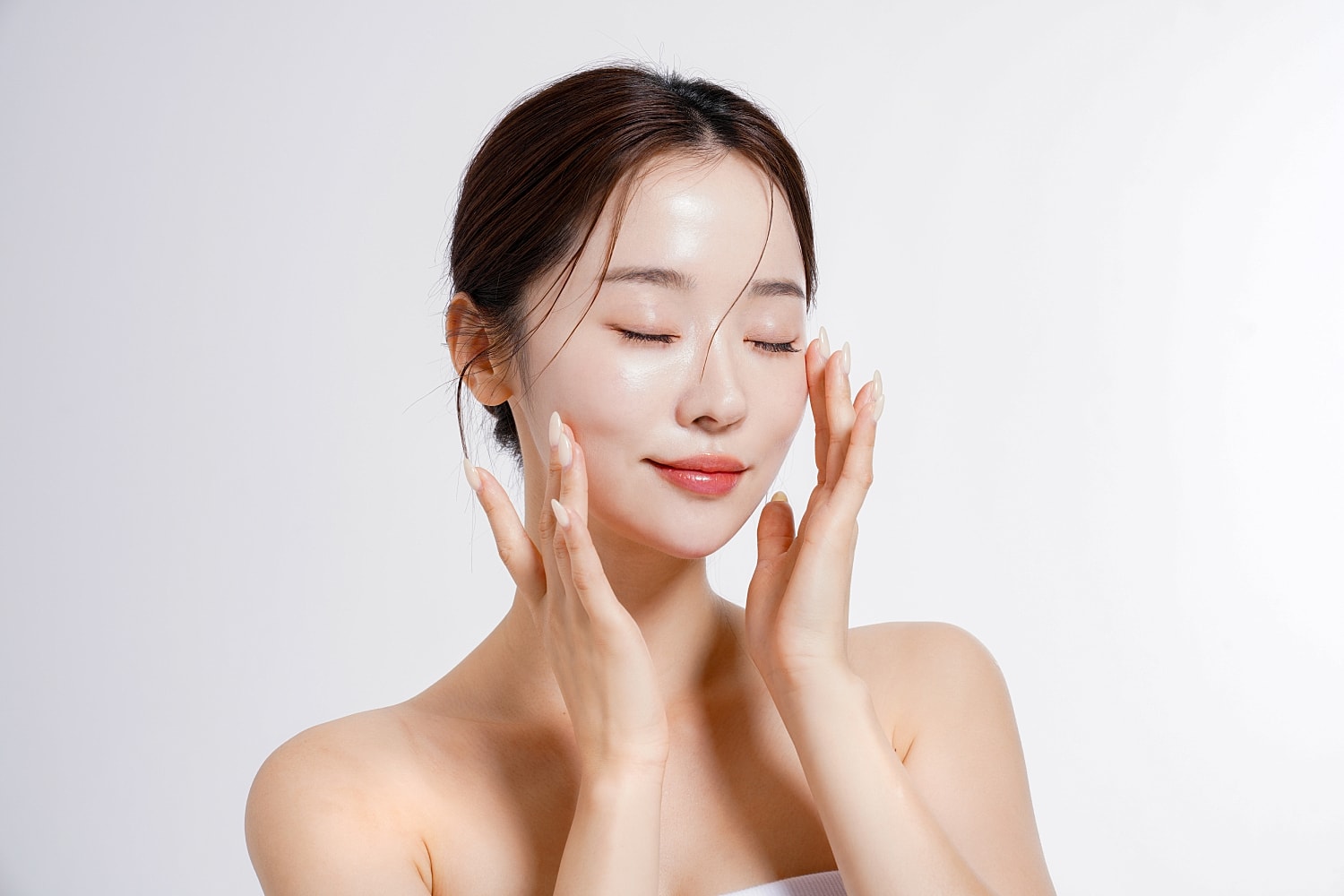 Woman applying skincare with a peaceful expression.