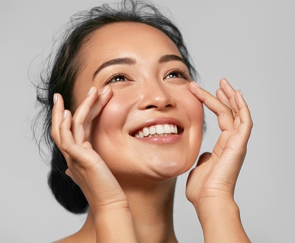 Smiling woman applying skincare on her face.
