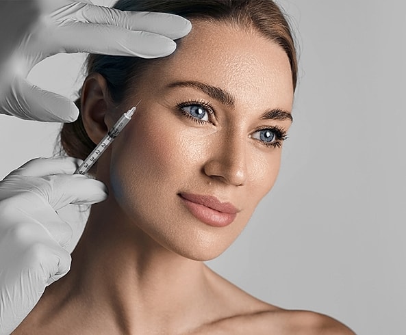 Beauty treatment with syringe on a woman's face.