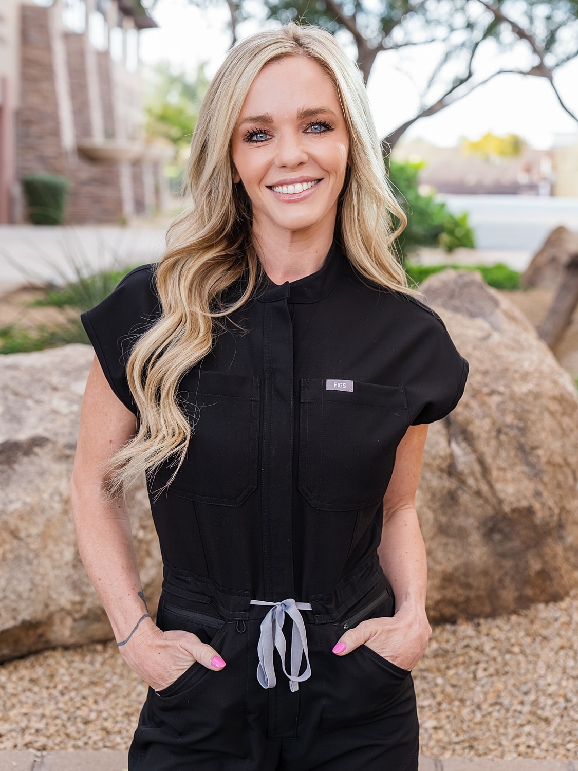 Dani RN Blume Medspa Smiling in black scrubs outdoors.