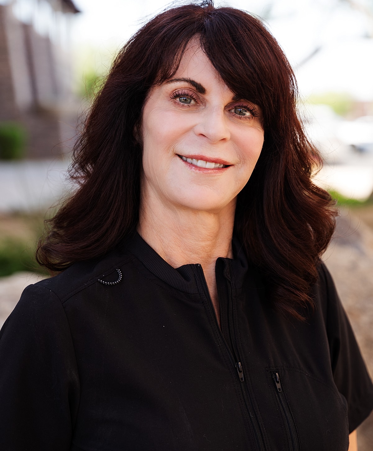 Smiling woman in a black outfit outdoors.