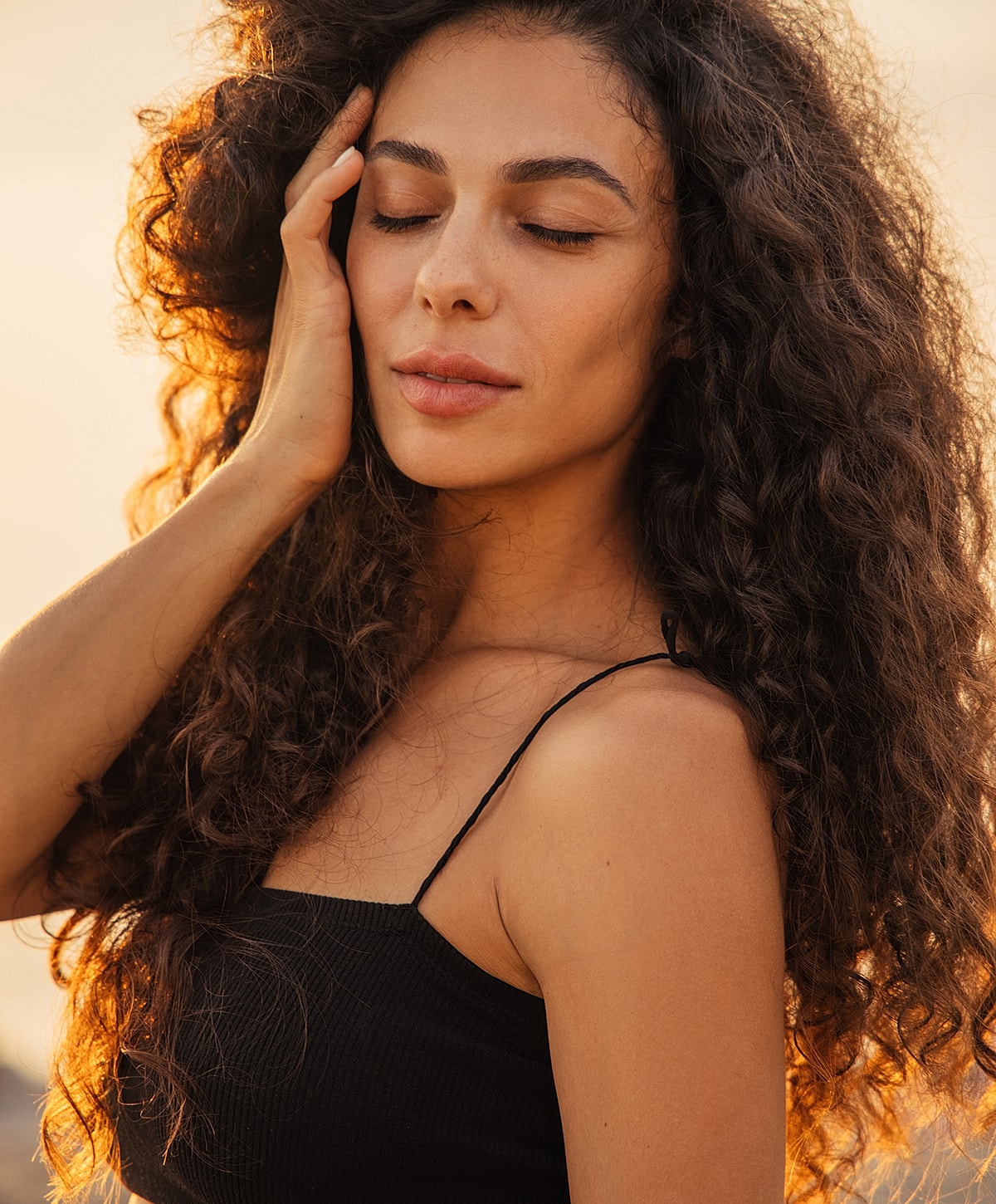 Woman with curly hair enjoying sunlight.