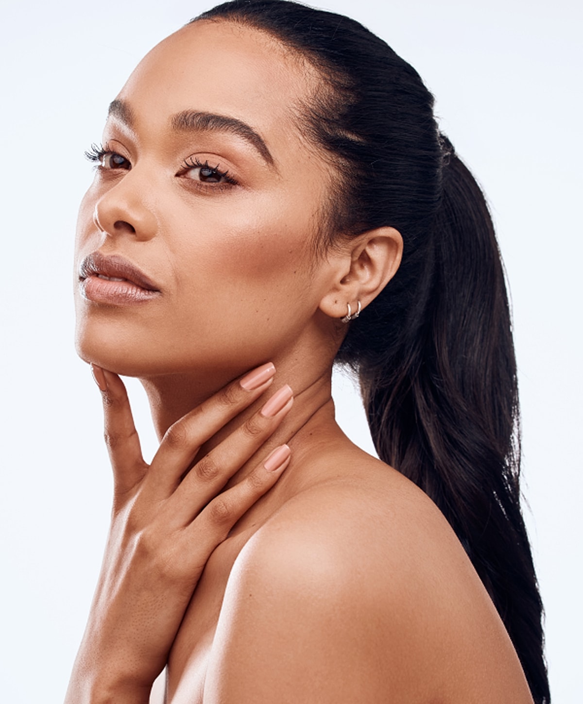 Woman with gray hair gently touching her face.