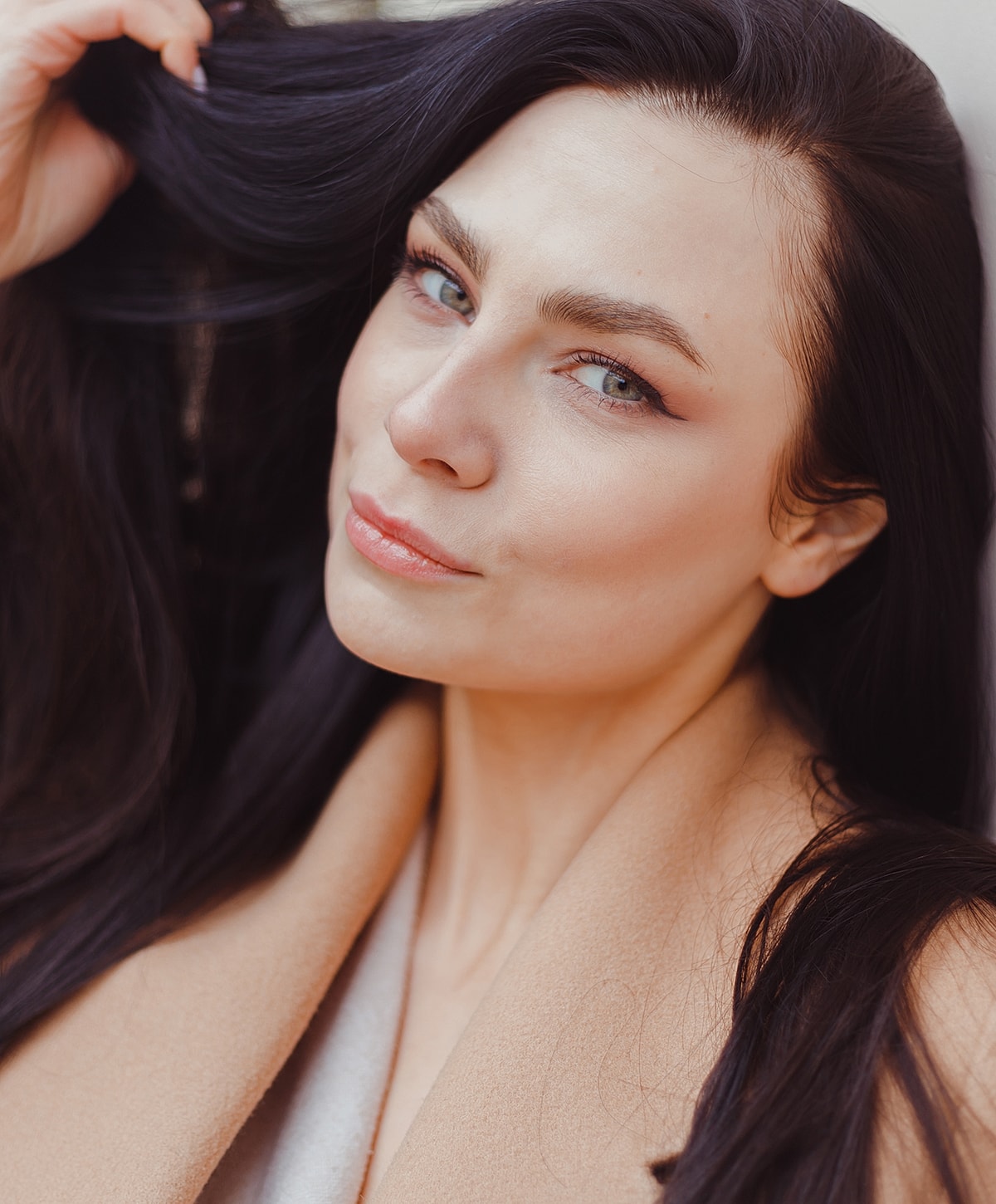 Woman with gray hair gently touching her face.