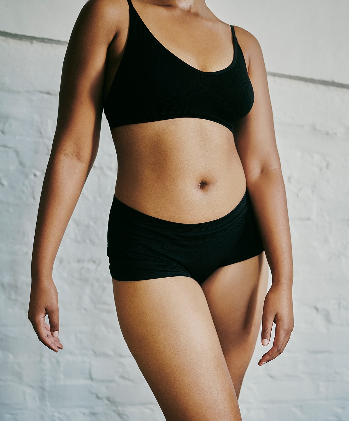 Model wearing black lingerie against white background.