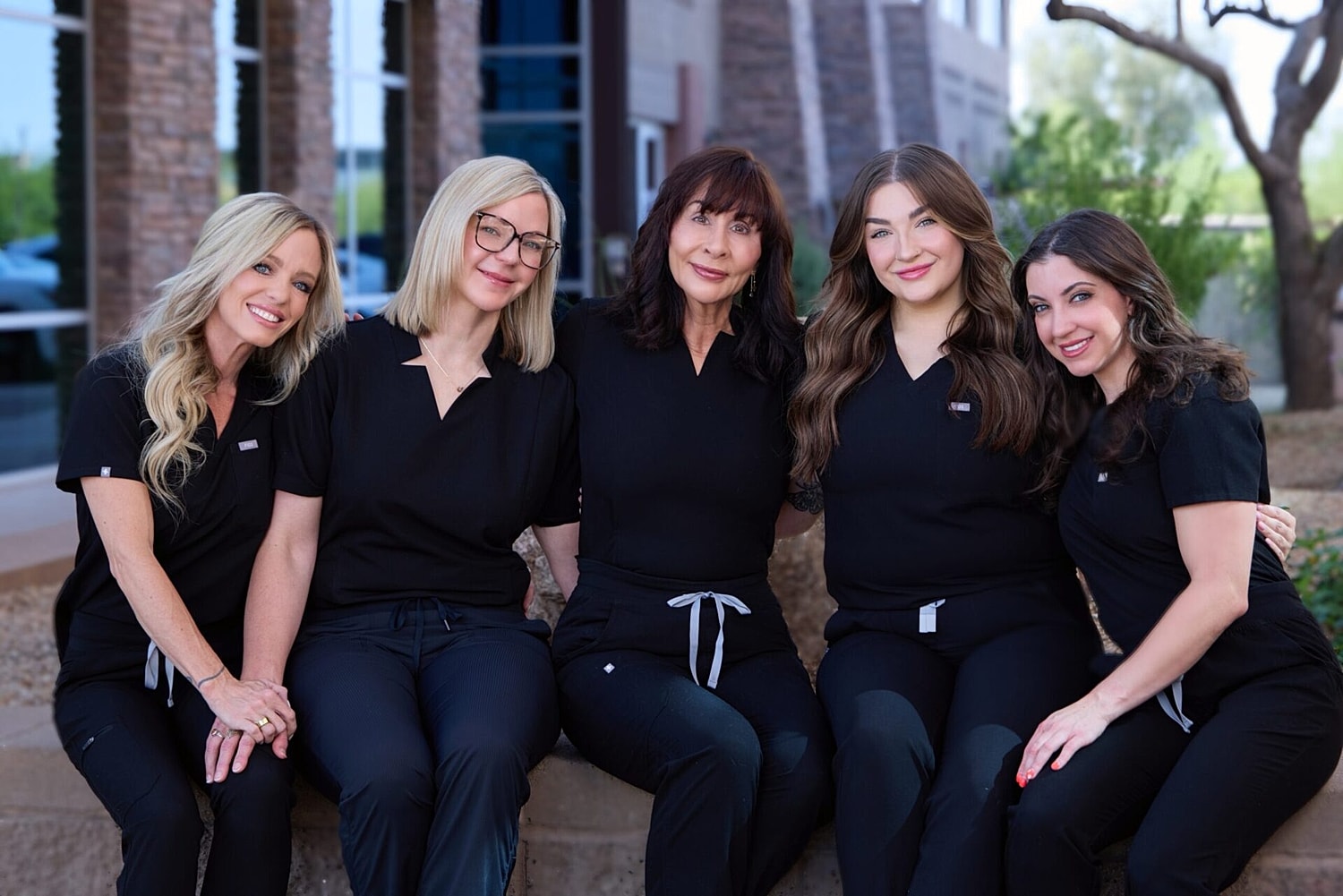 Healthcare team posing outdoors in black scrubs.