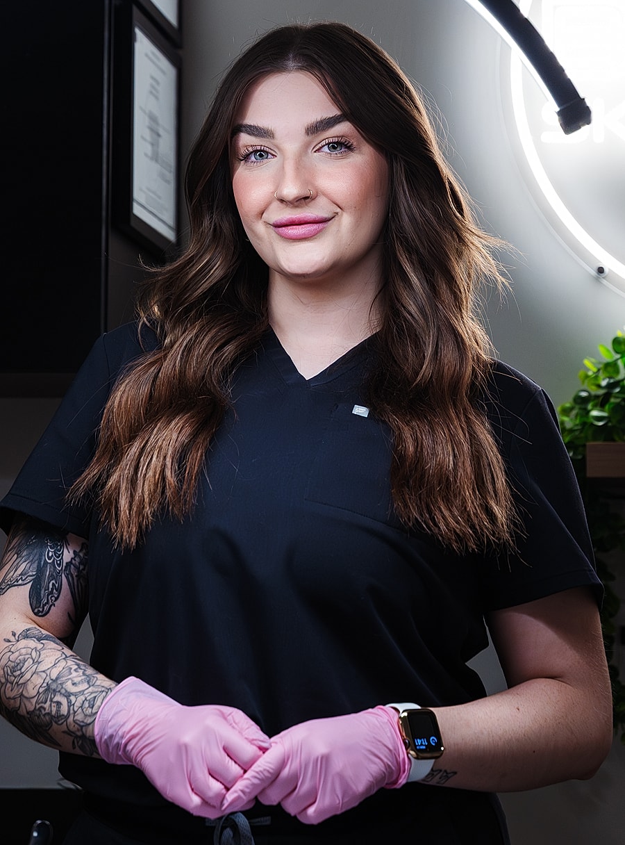 Woman in black scrubs wearing pink gloves.