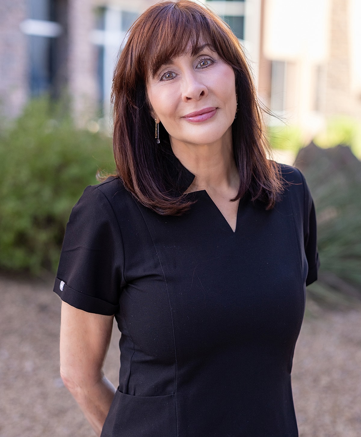 Smiling woman outdoors in black dress.