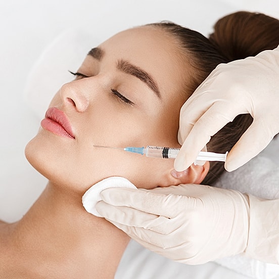 Woman receiving cosmetic injection treatment on face.