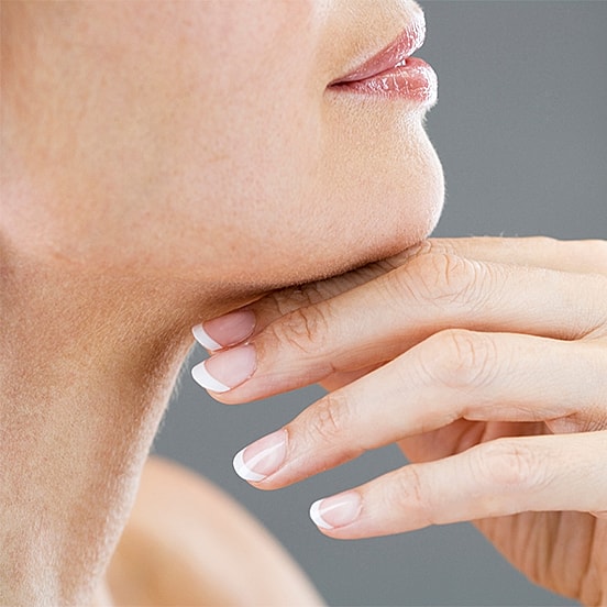 Woman resting chin on hand, soft background.