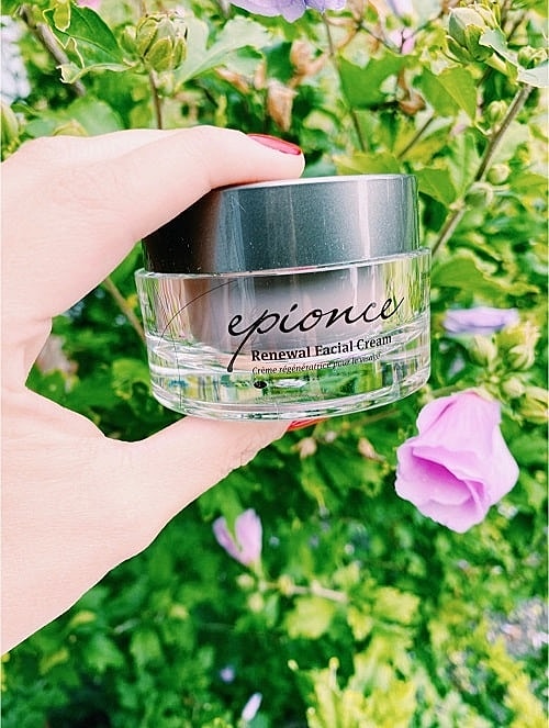 Hand holding Epionce Renewal Facial Cream jar.