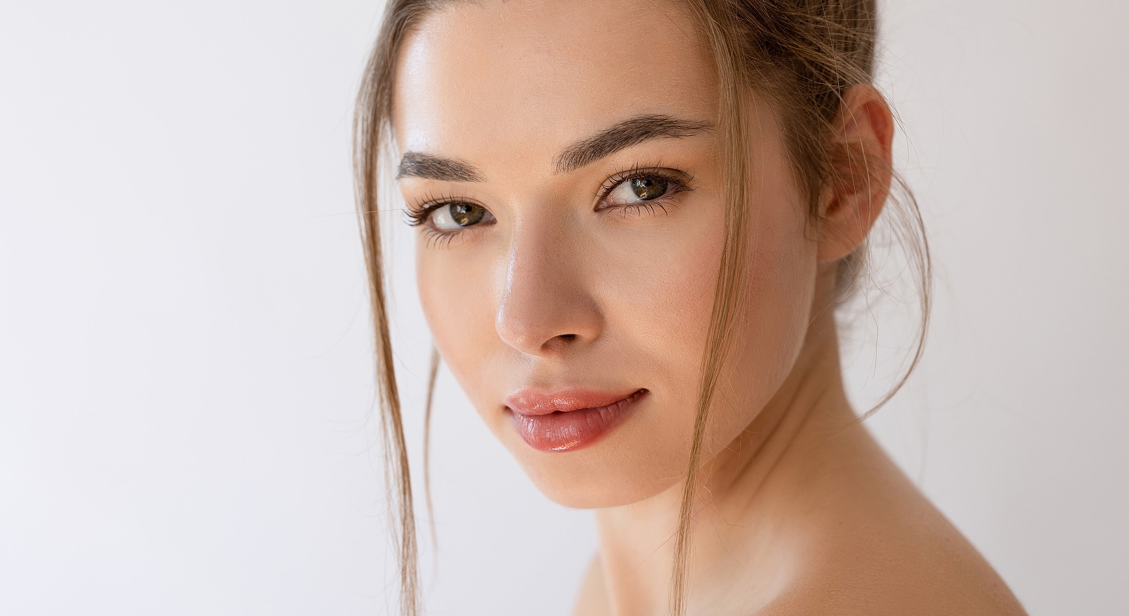 Applying cream to her face in bathroom mirror.