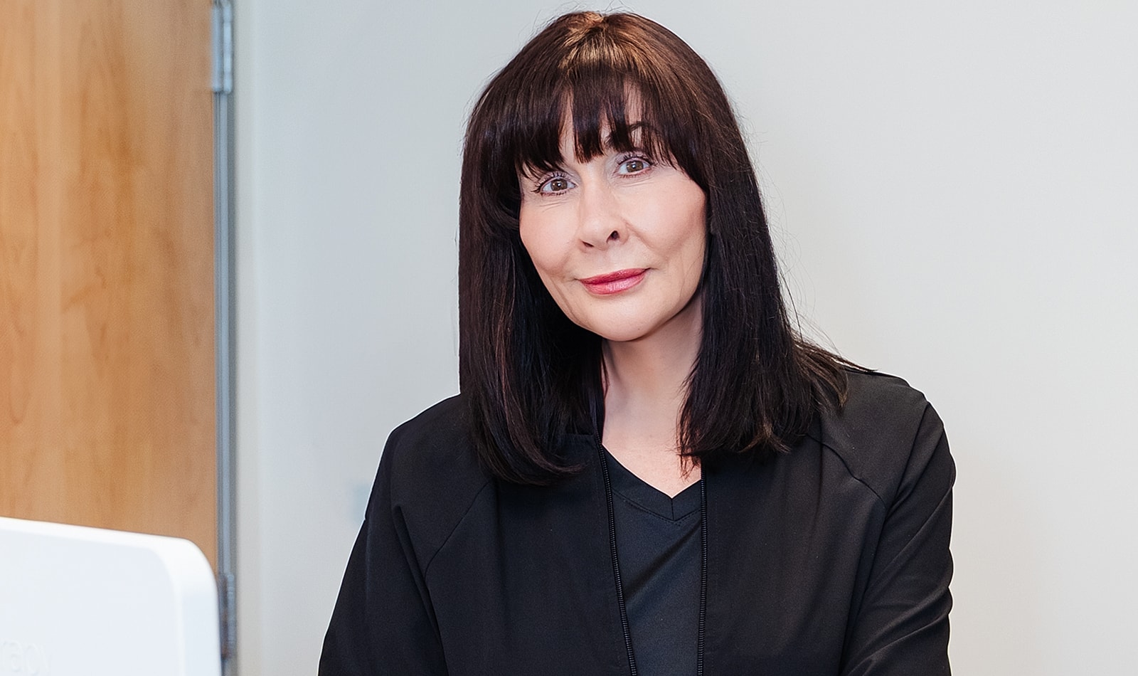 Woman with long black hair in professional attire.