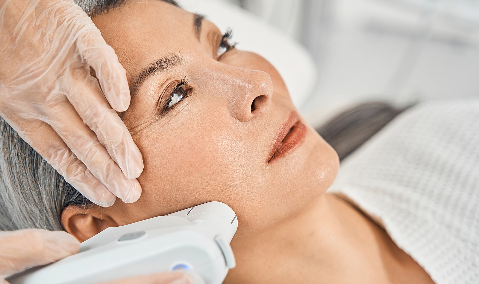 Facial treatment with device and gloved hands.