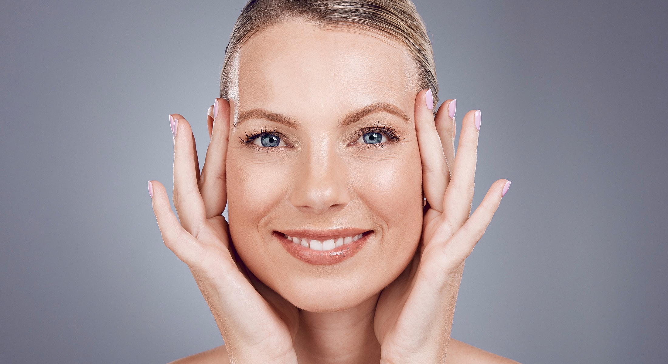 Smiling woman touching her face gently.