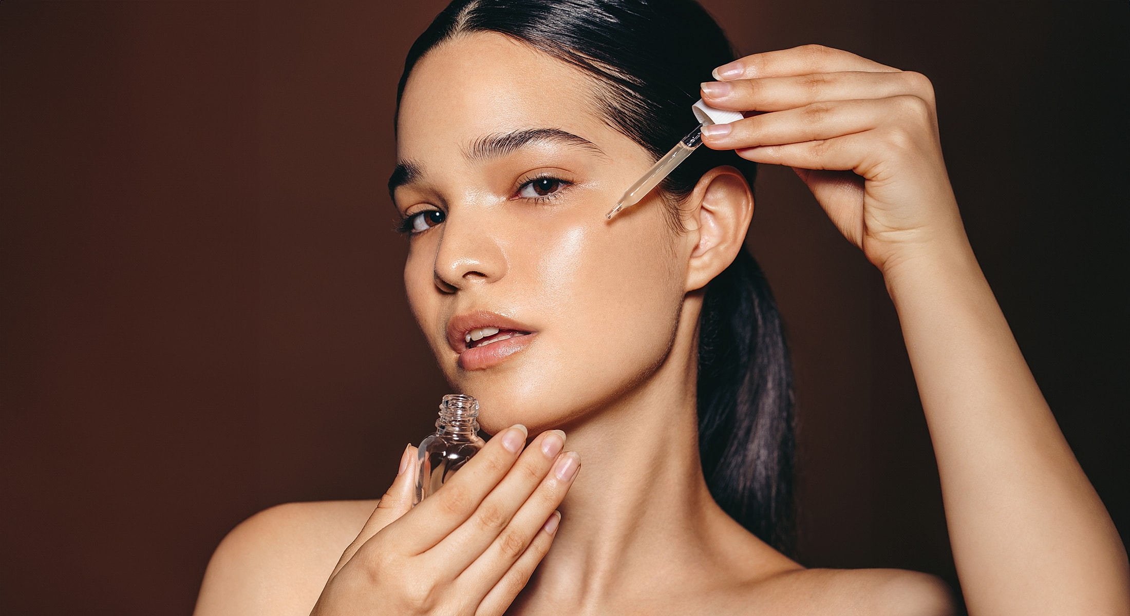 Woman applying serum to her face.