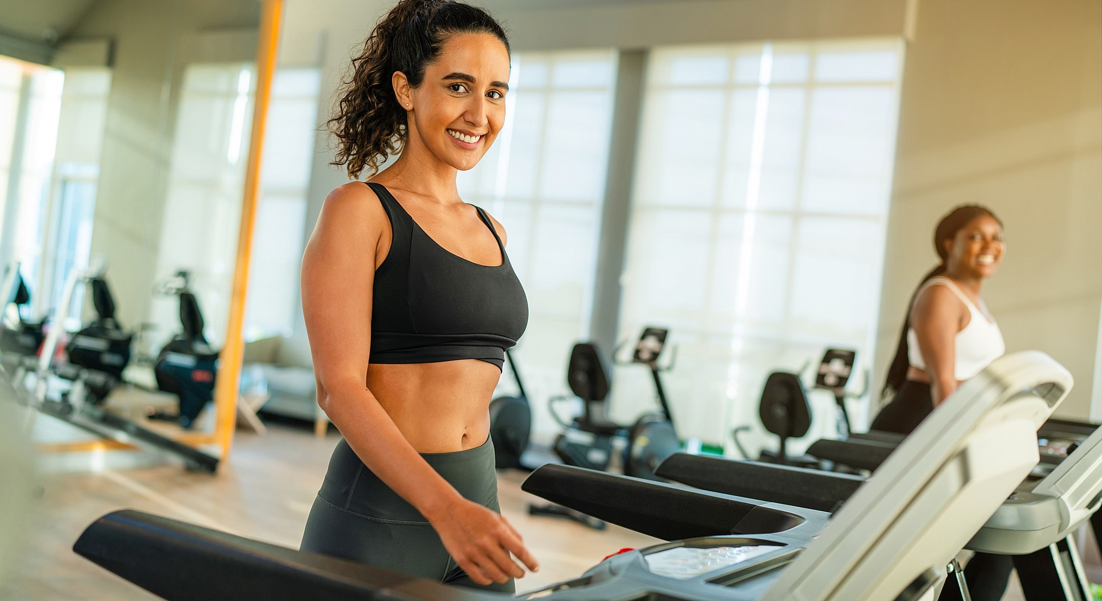Women exercising on treadmills in gym.