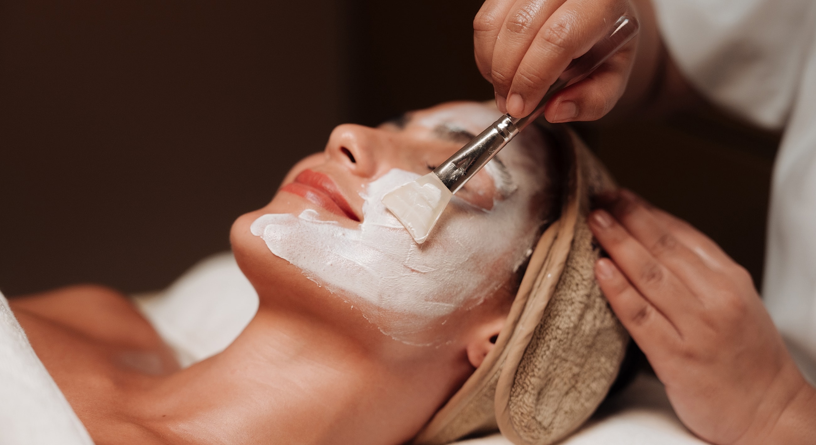 Applying facial mask in spa treatment session.