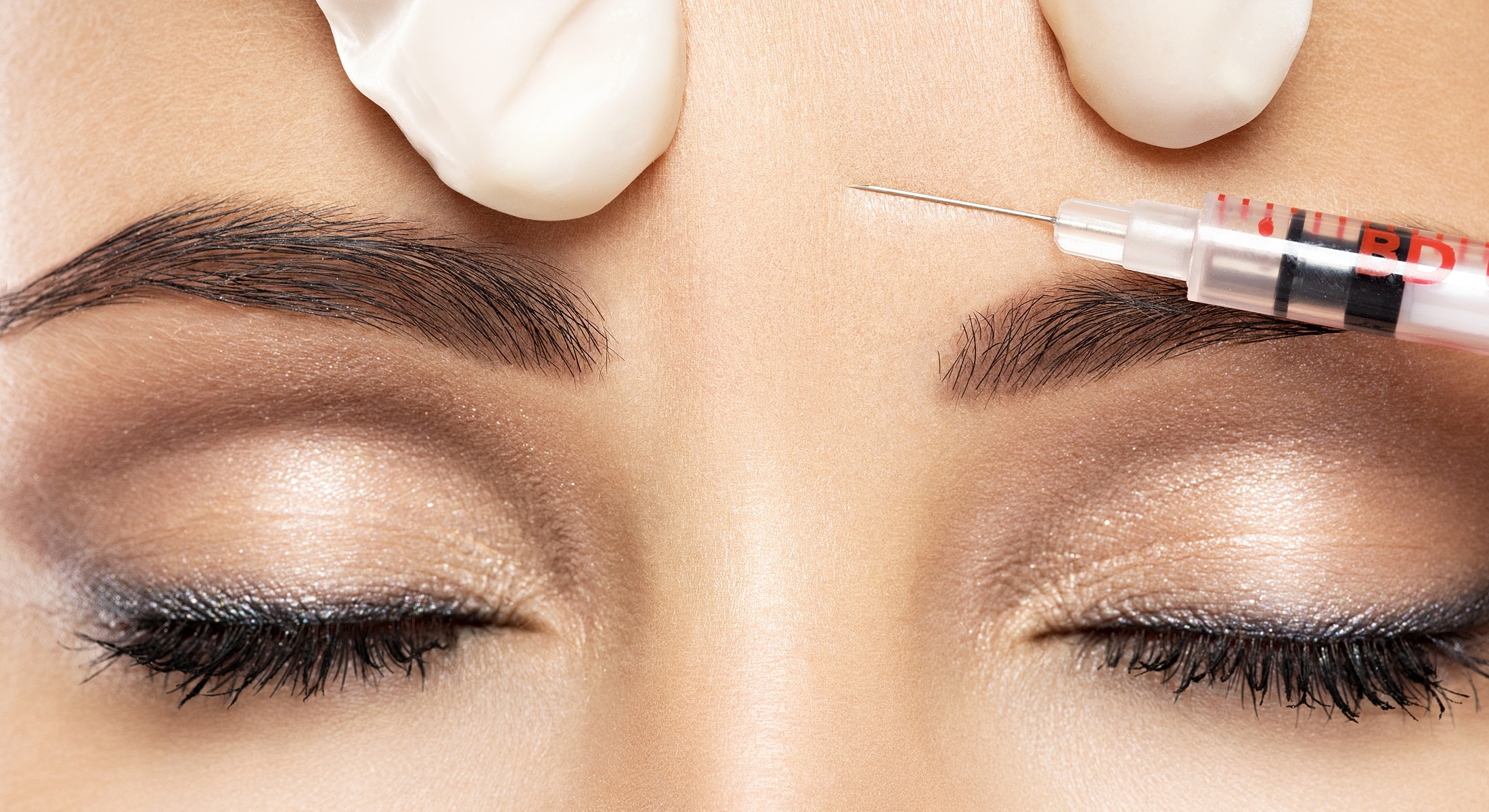 Cosmetic procedure with needle near closed eyes.