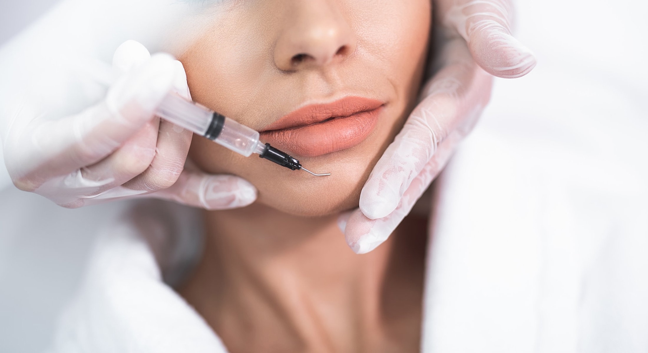 Cosmetic procedure with syringe on lip area.