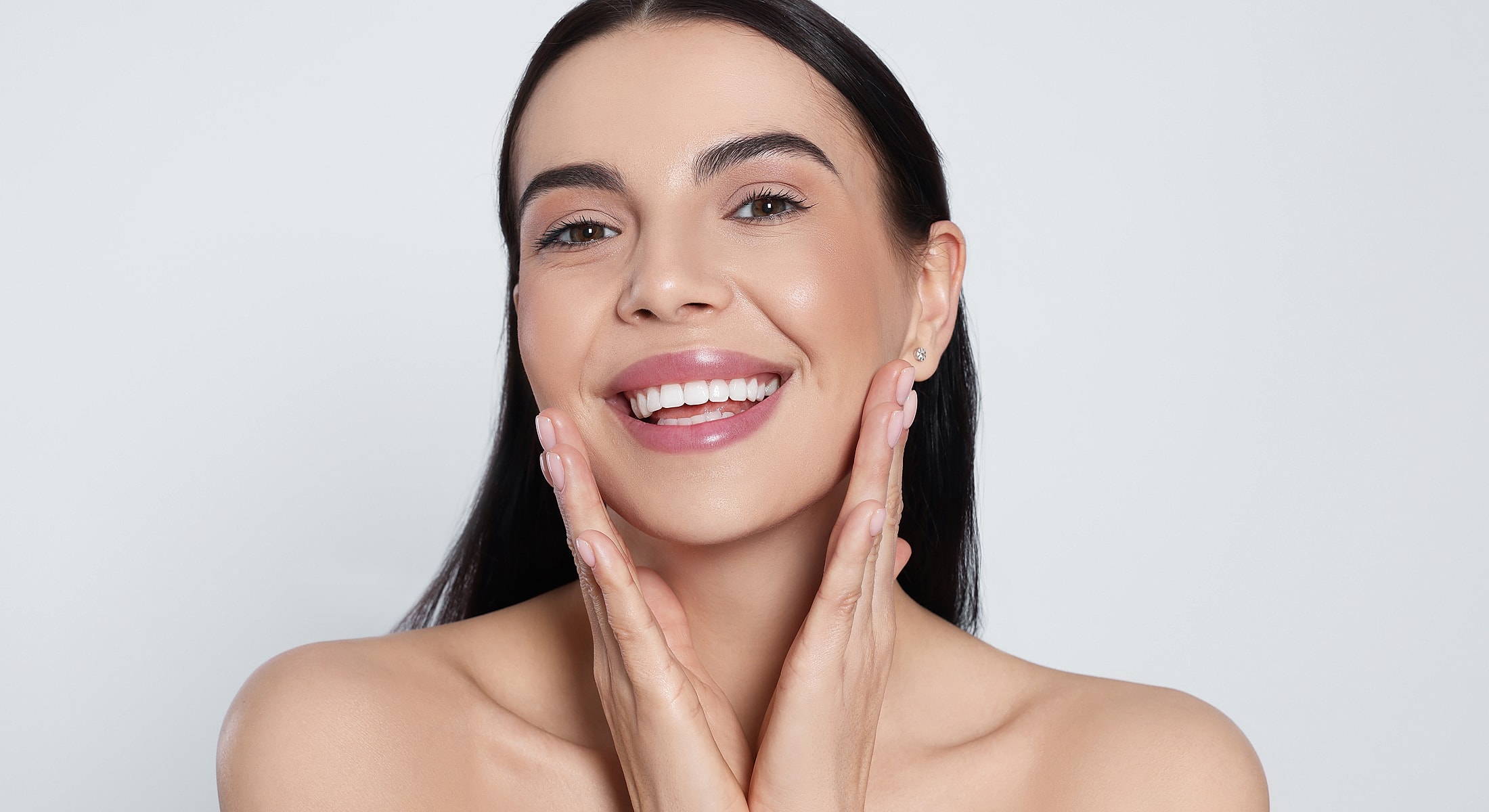 Smiling woman touching her face and glowing skin