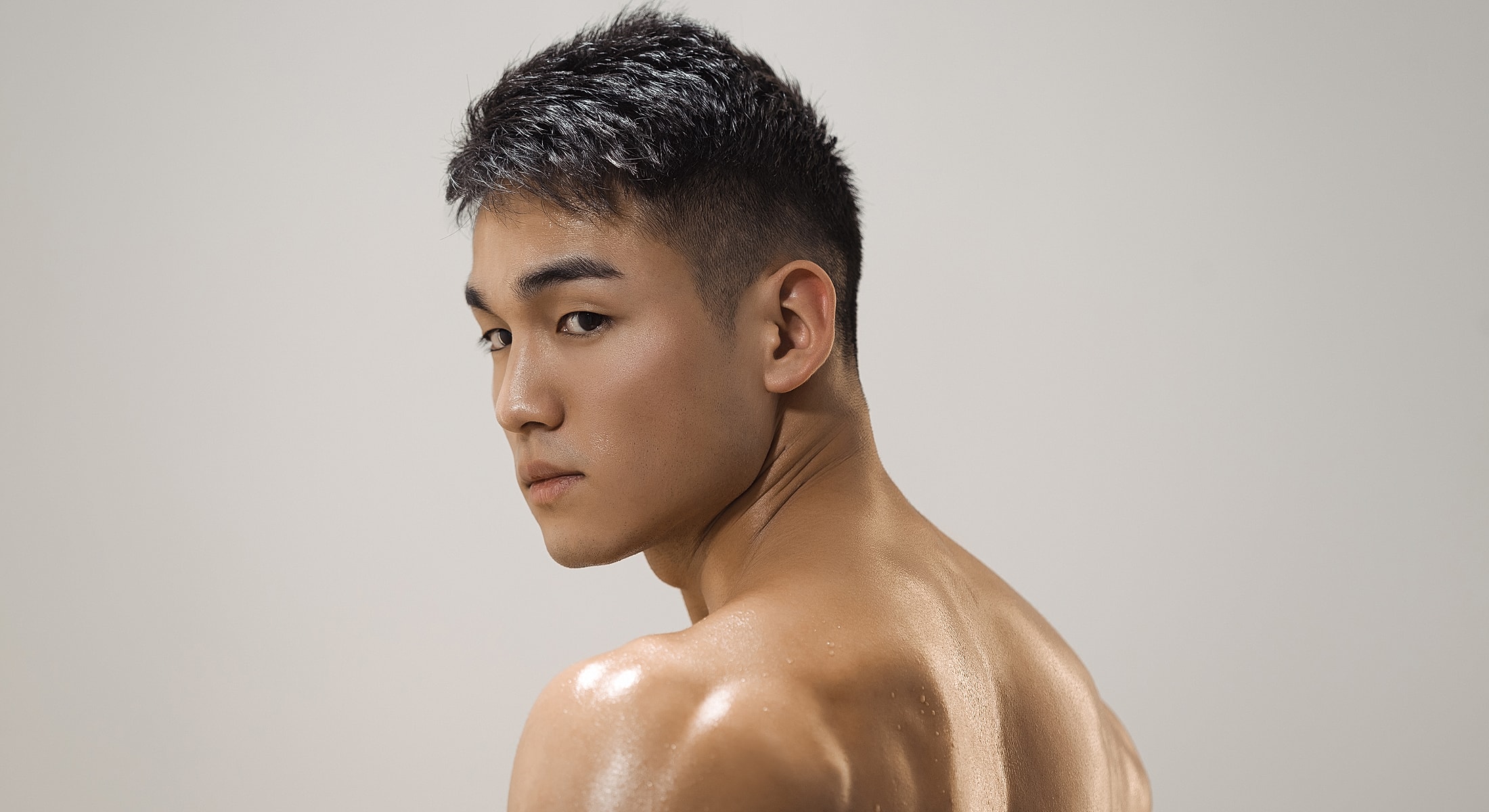 Young man with short hair, looking over shoulder.